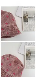 Detail shot of pink butterfly embroidery on washed denim bucket hat with wide brim