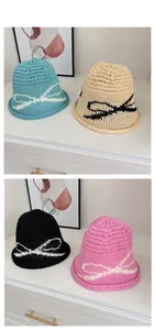 Detail of four knit bucket hats with contrast bow patterns in blue, beige, black, and pink