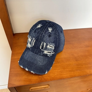 Vintage washed denim baseball cap with distressed LOVE patch on dark wood surface