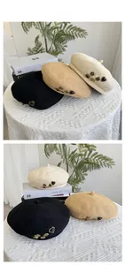 Close-up of knit beret hats with vintage metal heart and flower charms in three soft colors