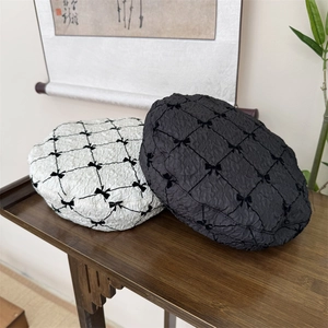 Black and white bow berets with diamond texture on a rustic wooden table background