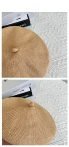 Flat lay of khaki knit beret showing textured weave and top decorative button detail