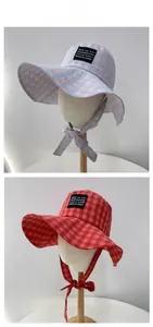 Detail of plaid wide brim sun hats with chin straps in blue-pink and red-orange colors