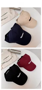 Detail of embroidered letters on four assorted colors of open-top cotton baseball caps