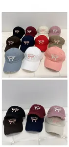 Close-up of distressed baseball caps in multiple colors with bow and letter embroidery
