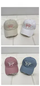 Close-up of distressed baseball caps with bow embroidery in beige, pink, blue and white