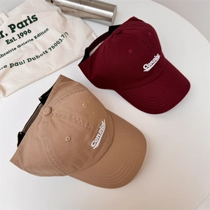 Classic embroidered letter baseball caps in burgundy and khaki on a canvas bag background
