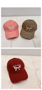 Detailed close-up of embroidered bow and text on vintage washed cotton baseball caps