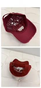 Detail of burgundy baseball cap showing metal adjustment buckle and distressed brim texture