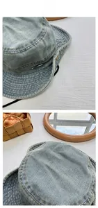 Detail view of light blue washed denim bucket hat with metal tag and stitching accents