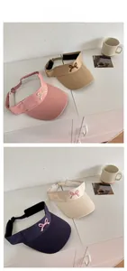 Detail view of cotton sun visors with bow embroidery in khaki, pink, beige and navy blue