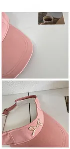 Detail of pink visor cap showing high-density cotton fabric and golden bow embroidery