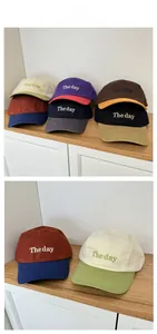 Detail of multi-color 5-panel caps with The Day embroidery on a wooden surface