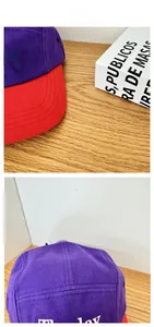 Detail view of purple baseball cap with red brim, cotton twill texture, and white embroidery