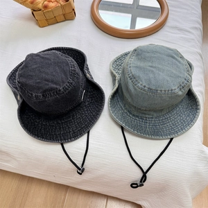 Flat lay of washed denim bucket hats in dark grey and light blue with windproof cords