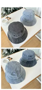 Detail of light blue and dark grey denim bucket hats with white letter embroidery