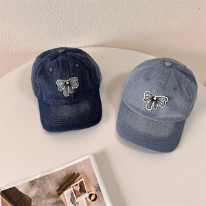 Washed denim baseball caps with striped bow patches in light and dark blue shades