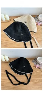 Close-up of hollow lace straw hat featuring scalloped edges and metallic min letter logo
