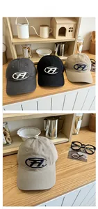 Détail de casquettes de baseball en coton avec broderie ovale en gris, noir et kaki