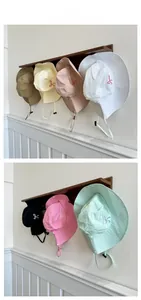 Detail showing various colors of sun hats with windproof drawstring on wooden hooks