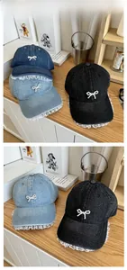 Detail of denim baseball caps with pearl bows and white lace trim on the brim edges