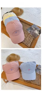 Detail of multi-color cotton baseball caps with heart embroidery in a lifestyle setting