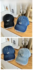 Close-up of denim baseball caps in black and blue with pearl bows and white lace edges