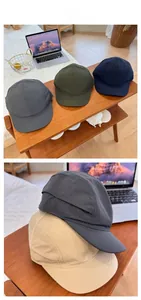 Detail of quick-dry nylon five-panel caps in dark grey and green on a wooden bench