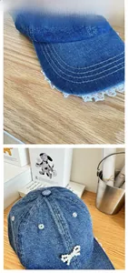 Detail of blue denim baseball cap featuring white lace trim and pearl bow embellishment