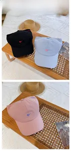 Detailed close-up of heart embroidery and stitching on cotton baseball caps