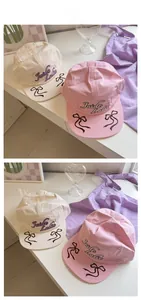 Detail of pink and cream baseball caps featuring purple embroidery and bow accents