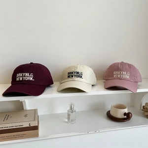 Berretti vintage con ricamo in bordeaux, beige e rosa su uno scaffale bianco