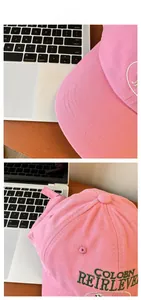 Détail de la casquette de baseball en coton rose avec broderie verte sur un bureau