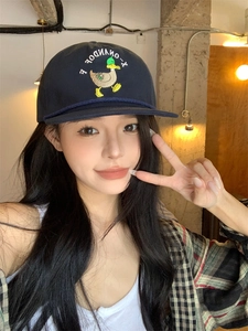 Detail of navy cotton baseball cap with yellow duck and text embroidery in a cafe