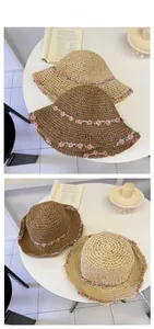 Detail of hand-woven straw hats featuring pink crochet flower decorations and wavy brims