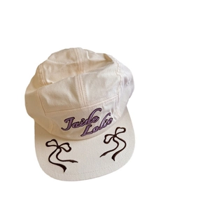 Beige 5-panel baseball cap featuring purple embroidery and side brown ribbon bows