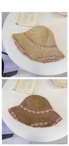 Detail of woven straw hats featuring pink floral embroidery in beige and coffee colors