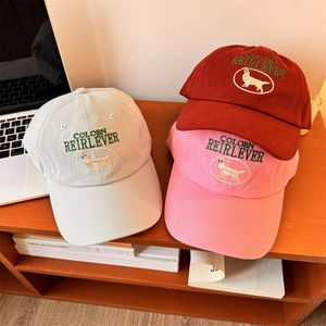 Trois casquettes de baseball brodées en gris, rouge et rose sur fond en bois chaud