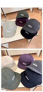 Detail of five-panel camper hats in multiple colors featuring outdoor mountain embroidery