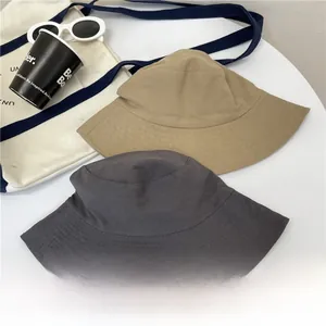 Flat lay of khaki and dark grey wide brim bucket hats with summer accessories
