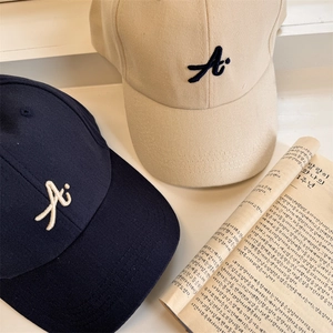 Berretti da baseball in cotone blu e beige con ricamo A su sfondo minimalista e pulito