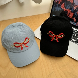 Black and light blue quick-dry baseball caps with red bow embroidery on a desk