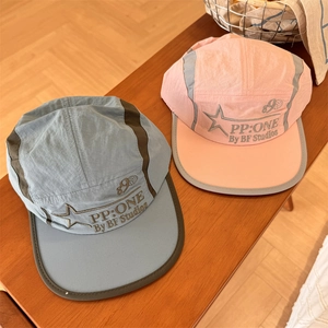 Outdoor quick-dry five-panel hats in light blue and pink on a wooden stool
