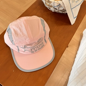 Pink and grey five-panel quick-dry camp hat with embroidery on a wooden bench