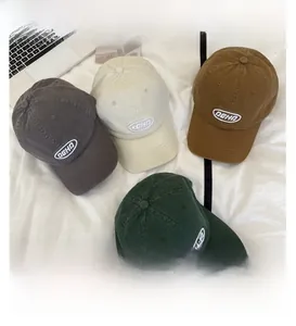 Draufsicht auf vier gewaschene Baumwoll-Basecaps in Grau, Beige, Braun und Grün mit AGHD-Logo