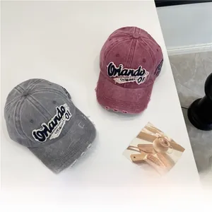 Macro shot of washed denim baseball caps with distressed holes and Orlando embroidery