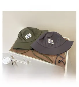 Close-up of military green bucket hat with adjustable windproof cord and logo label