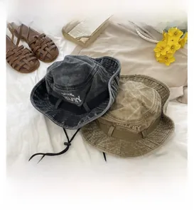 Détail de bobs en coton délavé gris et kaki avec broderie BELFRY et cordon