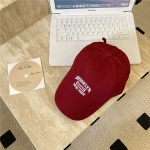Casquette vintage rouge foncé avec broderie Brooklyn sur un bureau en marbre