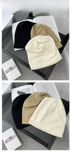 Detaillierte Strickstruktur von weichen Beanies in Schwarz, Khaki und Wollweiß